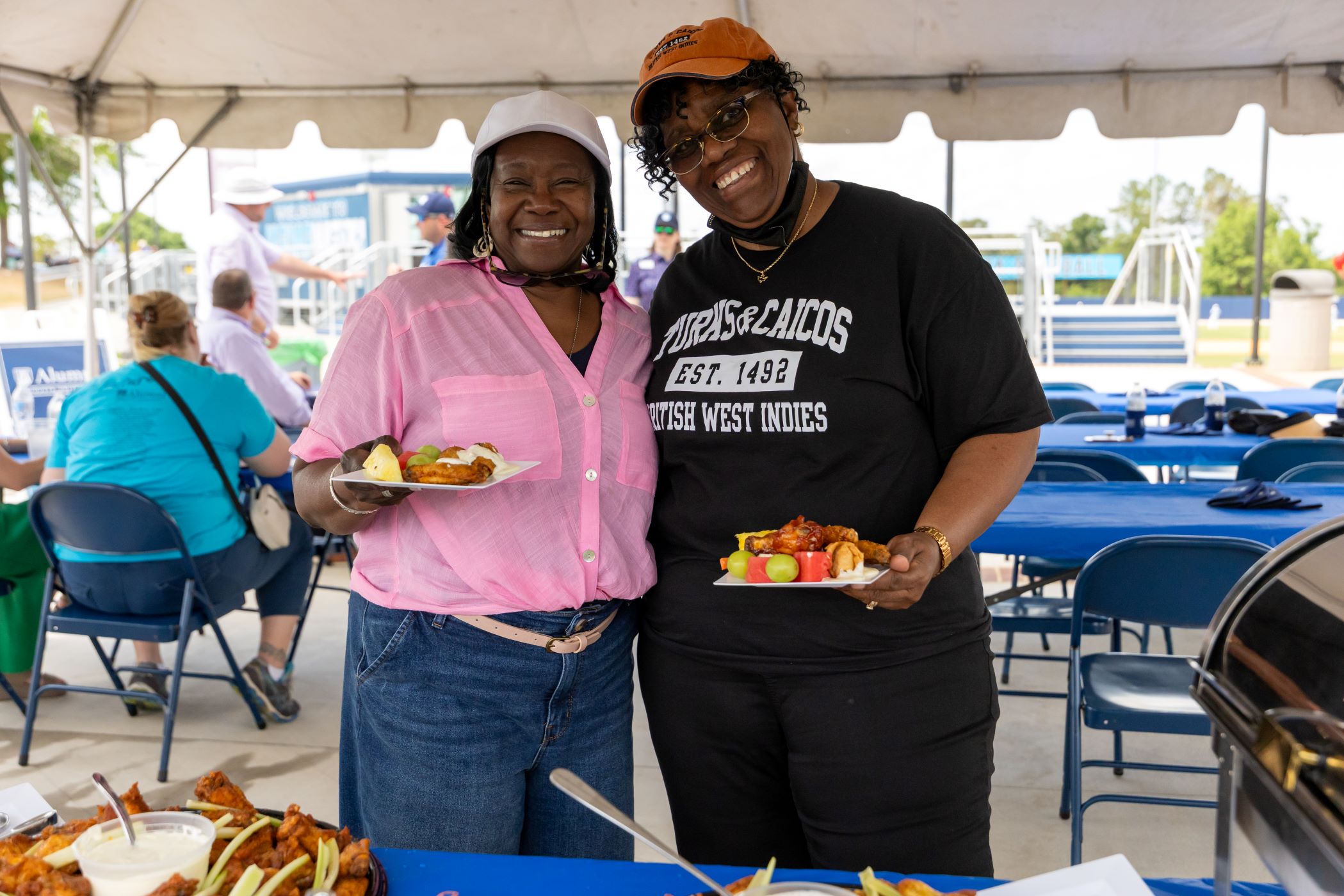 two alumni holding food at an event.
