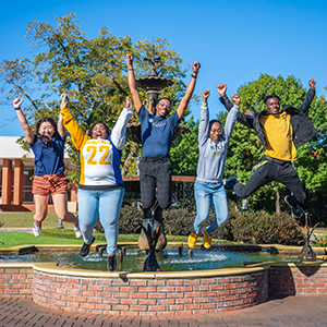 Students jumping in front of the fountain