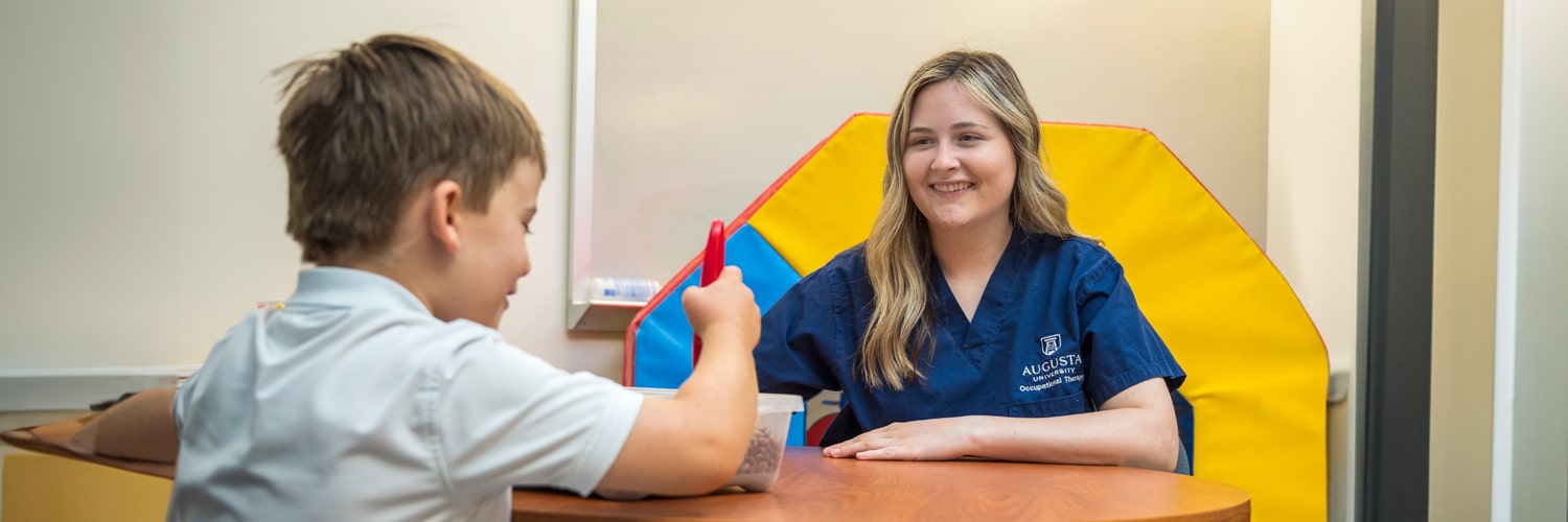 Occupational therapy student working with a child in the OT lab