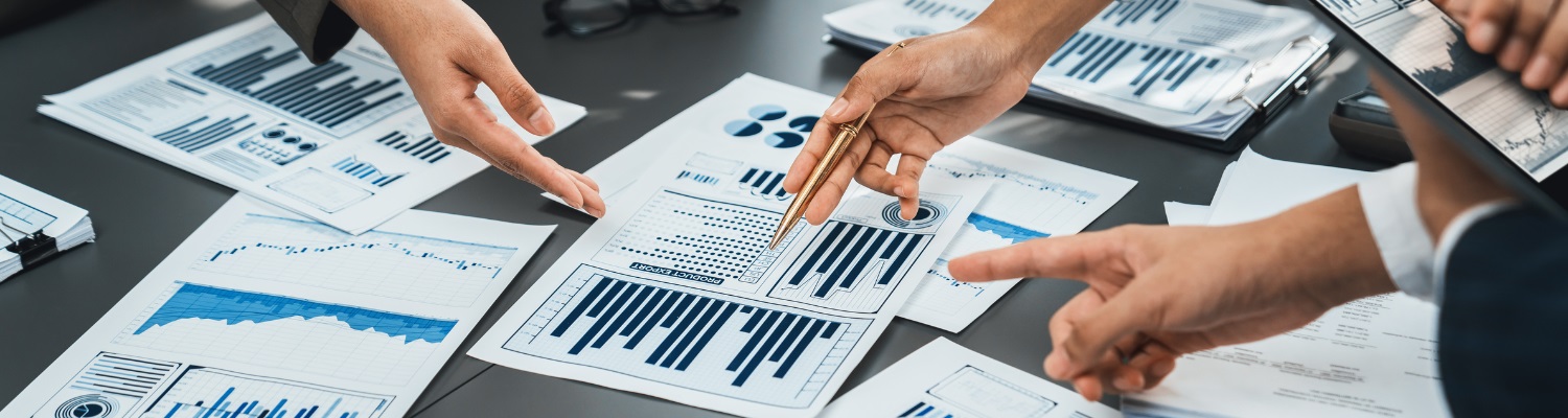 hands pointing to various papers with charts on a table