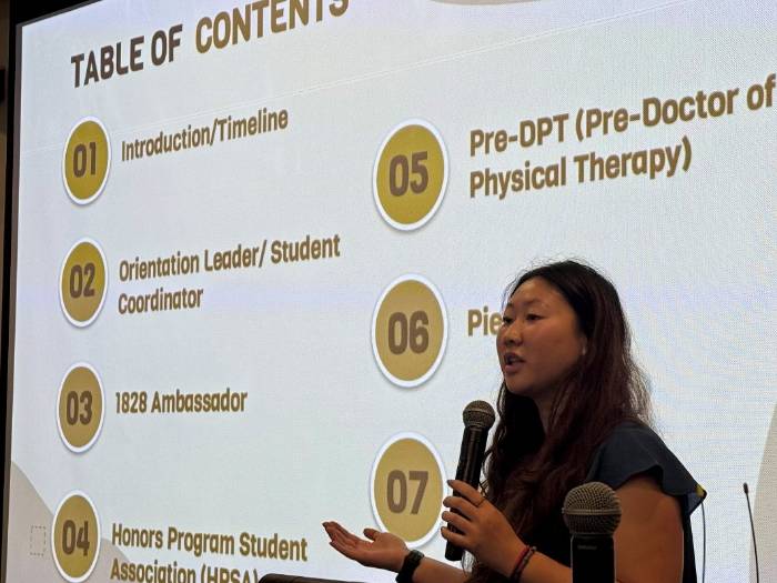COL capstone female student holding a microphone in front of a screen