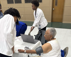 Student taking blood pressure of an elderly patient.