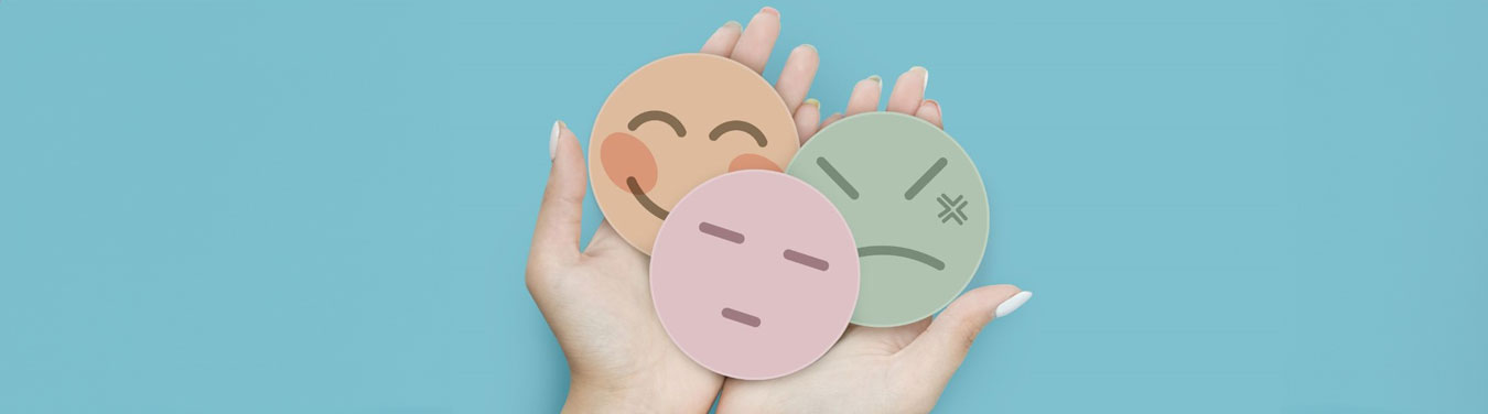 hands holding sad, happy and upset round paper faces