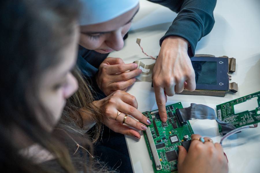 students hands pointing on a piece of technology