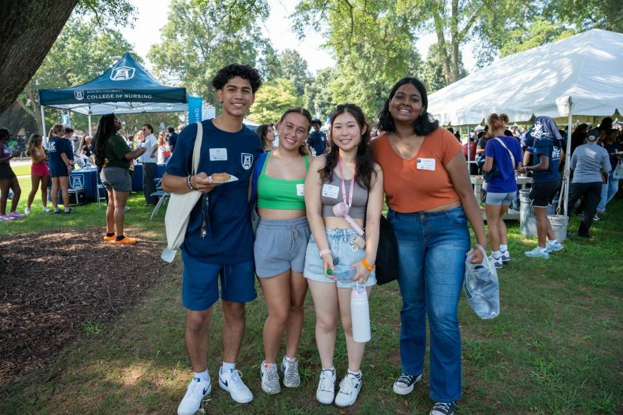 four students standing, smiling and holding food