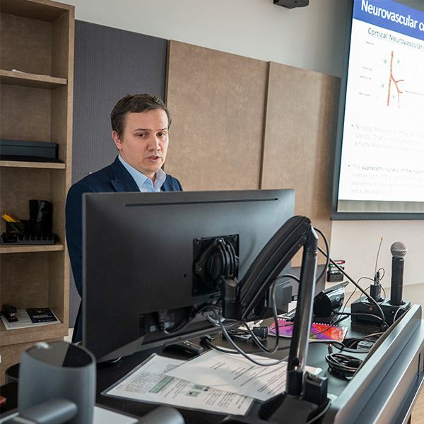 students with mentor postdoctoral fellow delivering presentation in front of projected slide