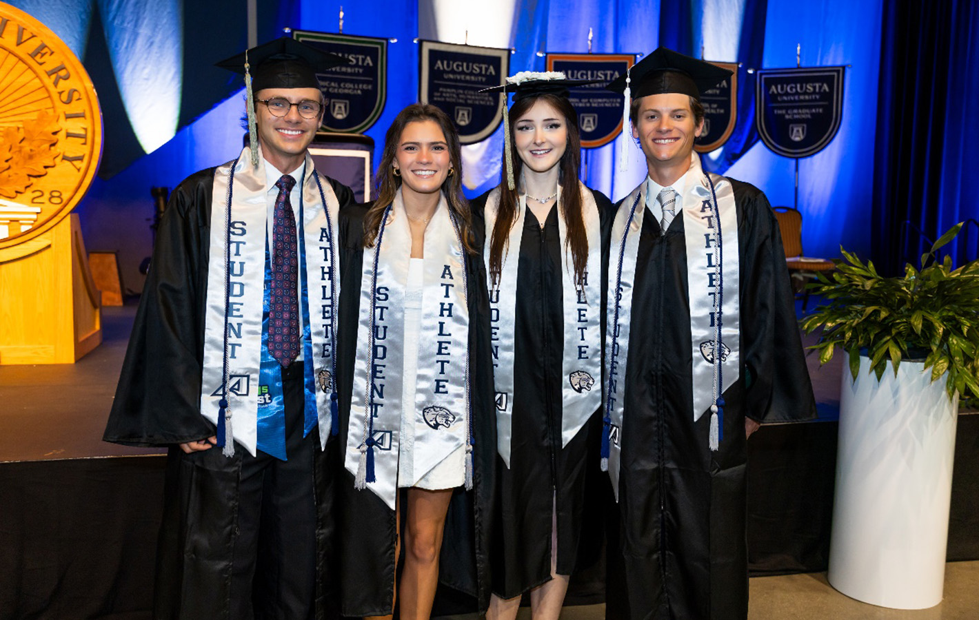 Four students standing together in caps and gowns
