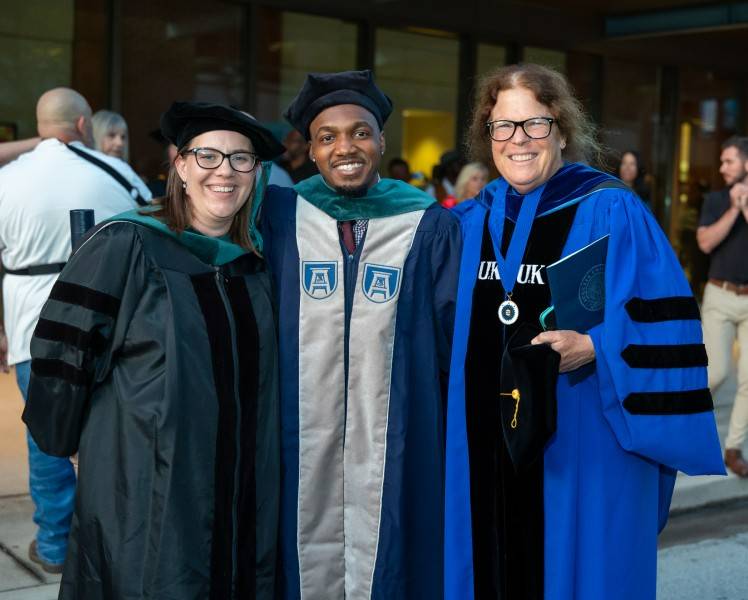 Faculty members standing with graduate