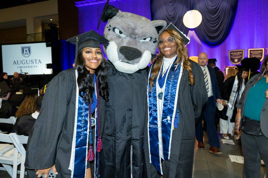 two girls standing with a gray cat mascot