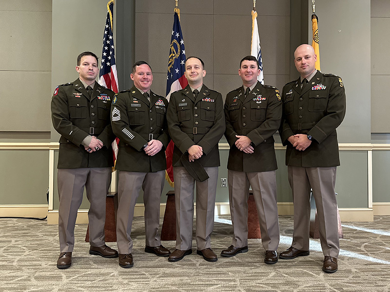 Cadets pose for a picture in front of posted flags