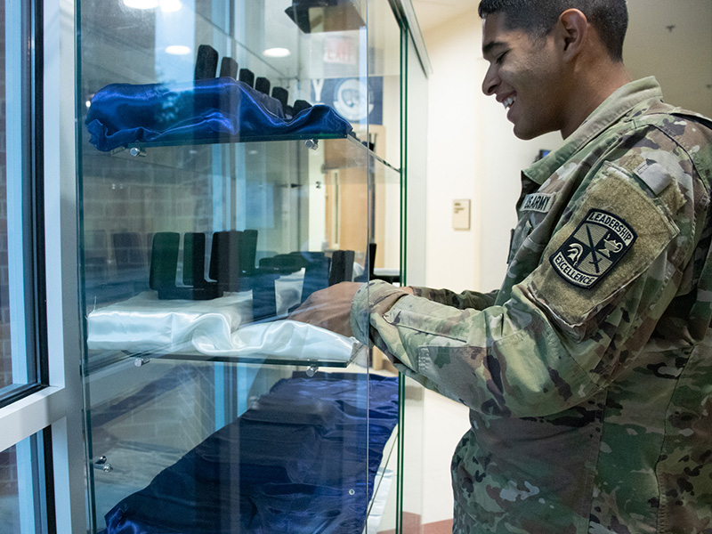 Cadet places a gold bar case into a glass display case