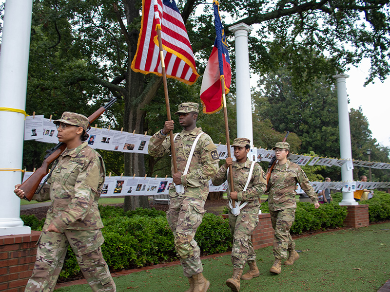 Cadets march in front of one another holding flags