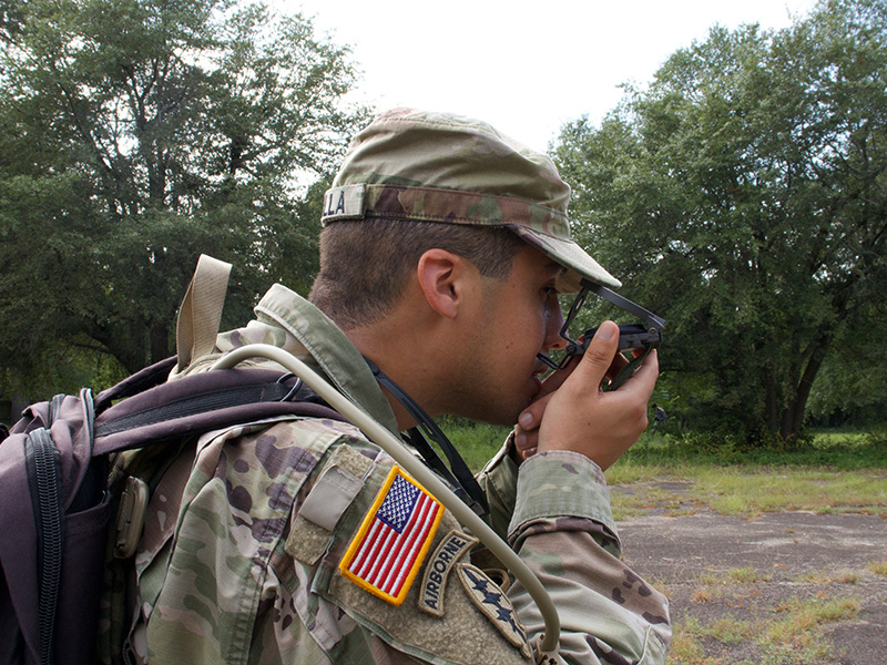 Cadet holds a compass to his face