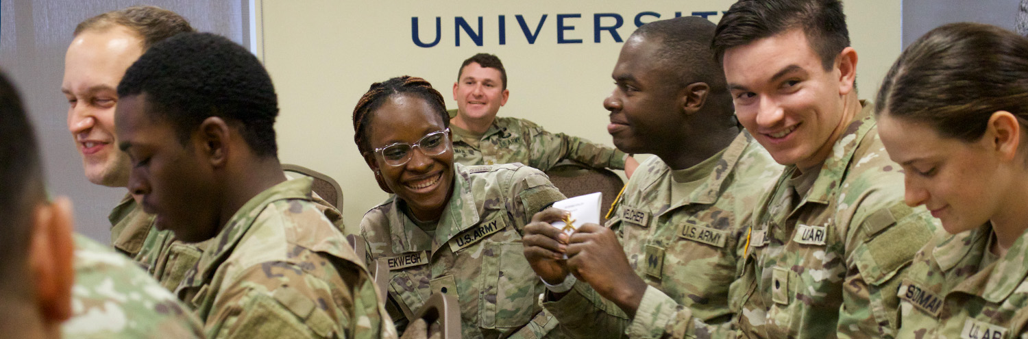 Cadet, seated among others, leans forward and smiles at her peers